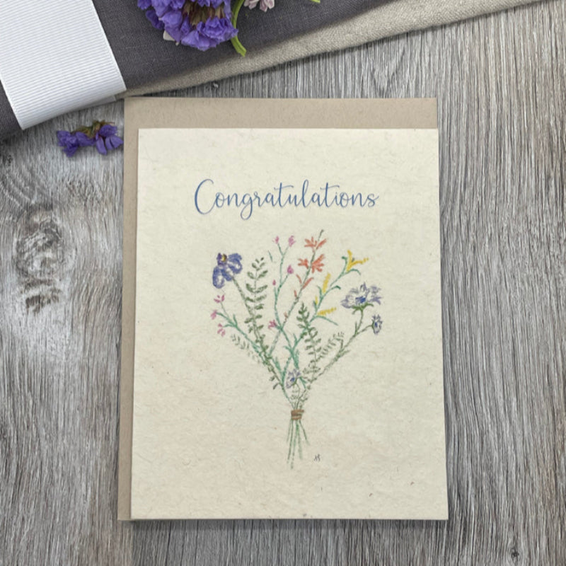 Greeting card with floral design and 'Congratulations' text on a wooden surface.
