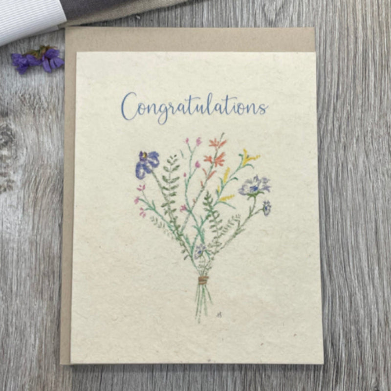 Greeting card with floral design and 'Congratulations' text on a wooden surface.