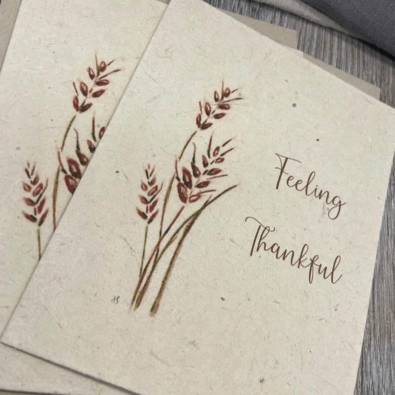 Kraft paper card with 'Feeling Thankful' text and leaf design on a textured surface.